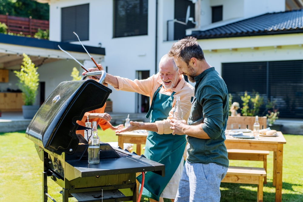father grilling with adult son in backyard